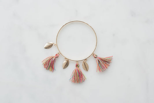 Gold boho bangle bracelet with multicolor tassels on white background