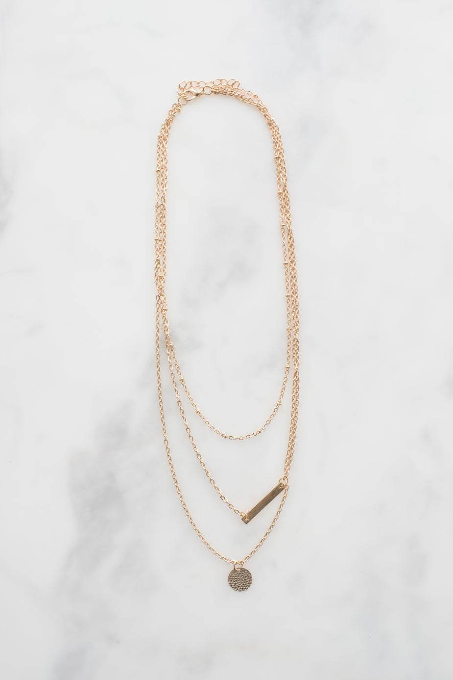 Dainty gold necklace with two pendants on a white background