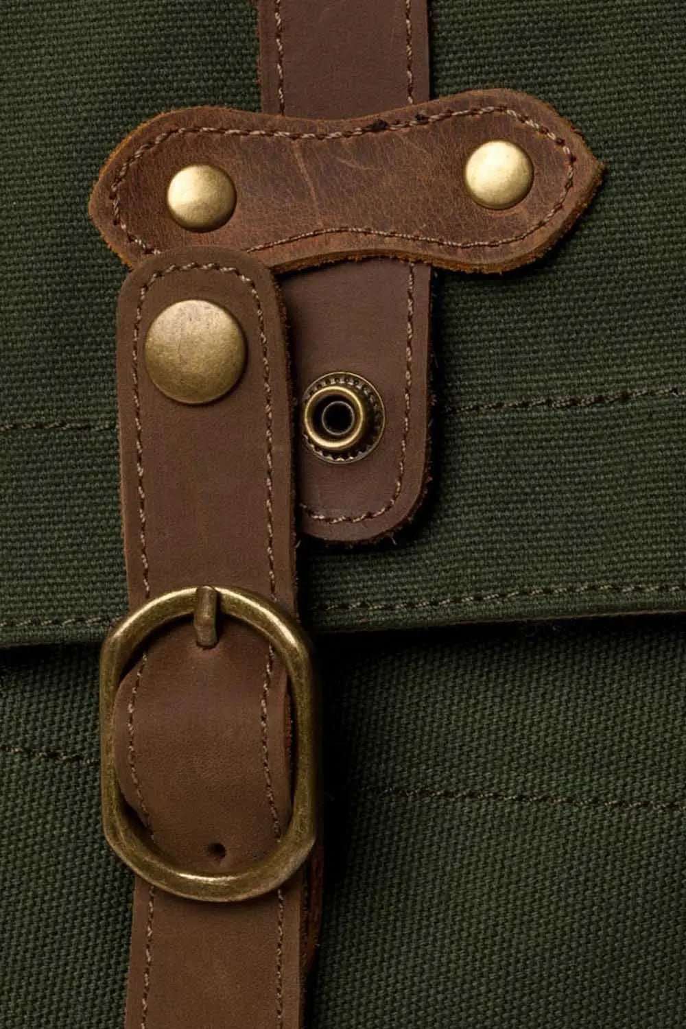 Scout Backpack in waxed canvas shown from the side with brass hardware and leather trim